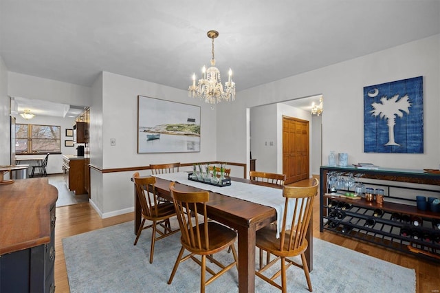 dining area featuring an inviting chandelier, baseboards, and wood finished floors