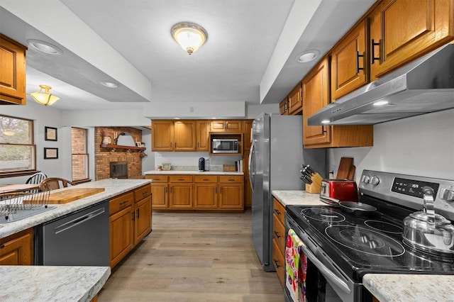 kitchen featuring appliances with stainless steel finishes, light countertops, brown cabinets, and under cabinet range hood