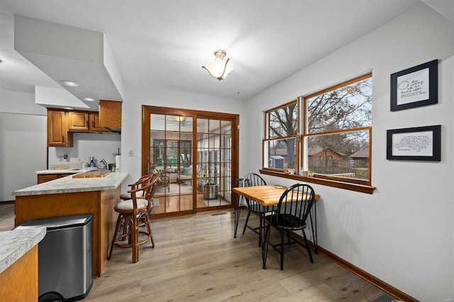 dining room with plenty of natural light, light wood-style flooring, and baseboards