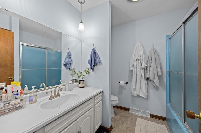 bathroom featuring toilet, vanity, visible vents, baseboards, and combined bath / shower with glass door