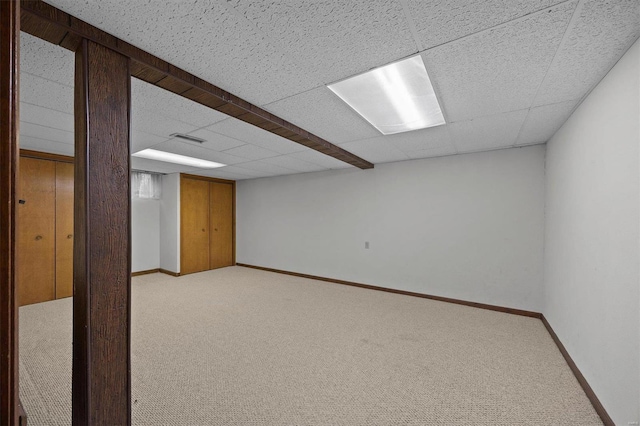 finished basement featuring a drop ceiling, carpet, visible vents, and baseboards