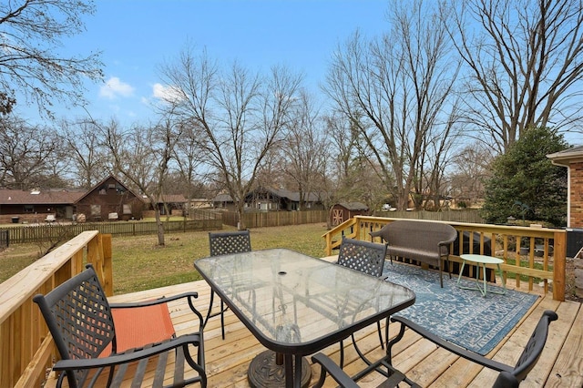 wooden deck featuring a fenced backyard, a lawn, and outdoor dining space