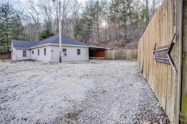 rear view of house featuring a shingled roof and fence