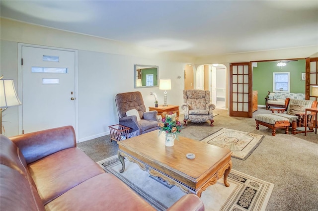 living room with baseboards, arched walkways, and carpet