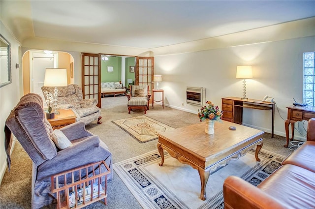 carpeted living room featuring baseboards, heating unit, and arched walkways