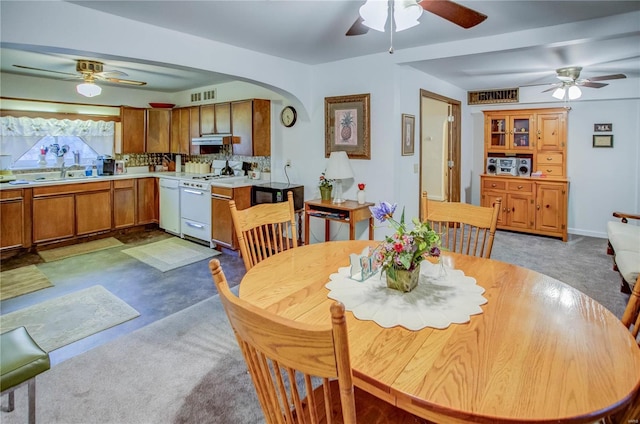 dining space featuring visible vents, baseboards, ceiling fan, light colored carpet, and arched walkways