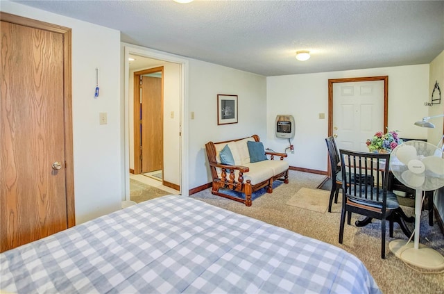 bedroom with heating unit, a textured ceiling, light carpet, and baseboards