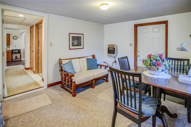 carpeted dining space featuring baseboards, heating unit, and a textured ceiling