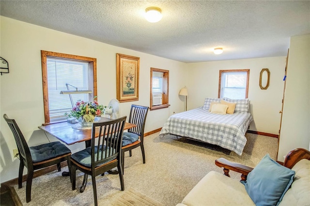 bedroom featuring light colored carpet, baseboards, and a textured ceiling