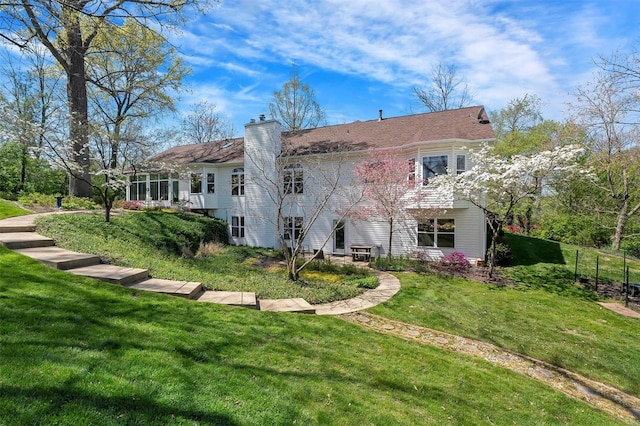 rear view of house featuring a chimney and a lawn