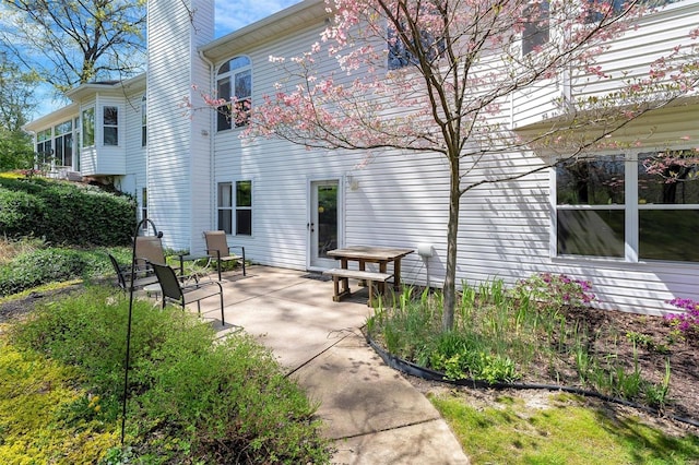 rear view of property featuring a chimney and a patio area