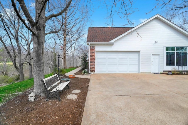 view of property exterior featuring driveway, brick siding, roof with shingles, and a garage