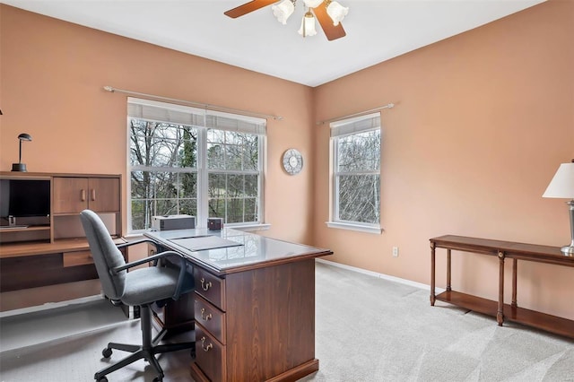 office area featuring baseboards, a ceiling fan, and light carpet