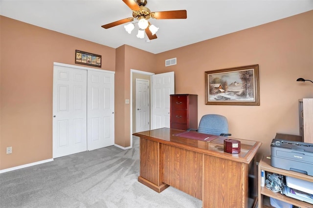 home office featuring light carpet, a ceiling fan, visible vents, and baseboards