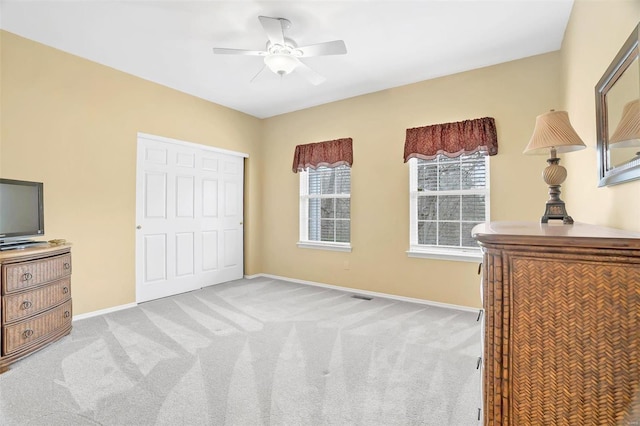 unfurnished bedroom featuring baseboards, a closet, a ceiling fan, and light colored carpet