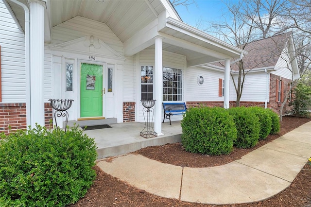 property entrance with brick siding and a porch