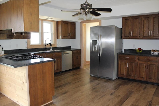 kitchen featuring a peninsula, dark wood-type flooring, a sink, appliances with stainless steel finishes, and dark countertops