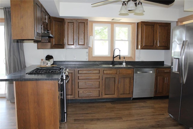 kitchen featuring dark countertops, appliances with stainless steel finishes, dark wood-type flooring, a ceiling fan, and a sink