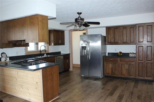 kitchen with dark countertops, dark wood-style floors, stainless steel appliances, and a sink