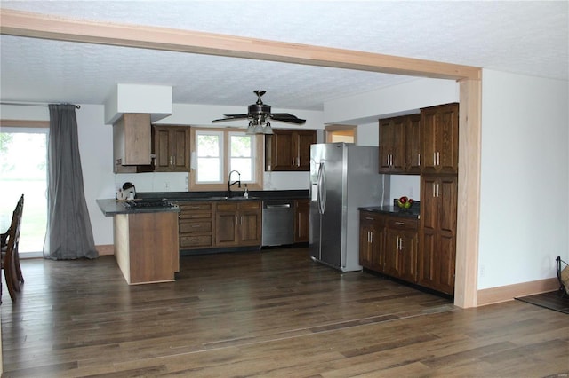 kitchen with dark wood-style floors, appliances with stainless steel finishes, dark countertops, and a sink