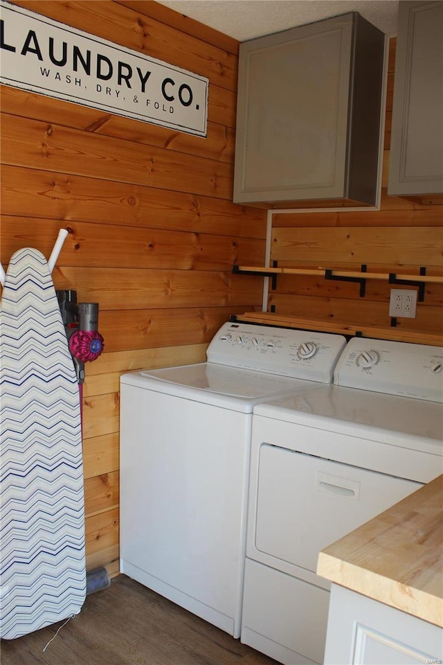 laundry area featuring dark wood-type flooring, washing machine and dryer, cabinet space, and wood walls