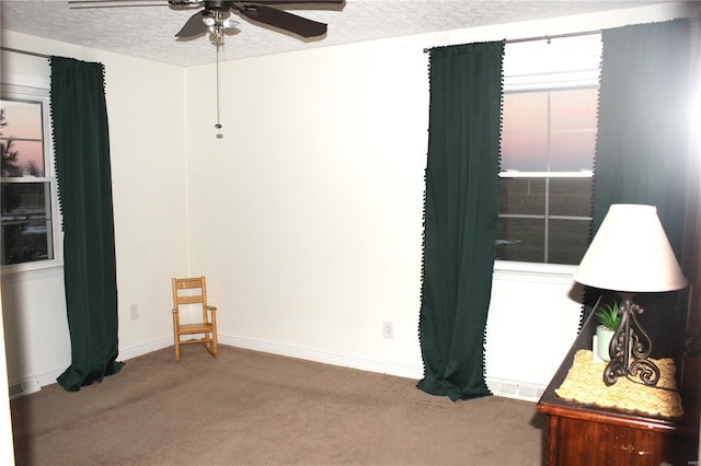 unfurnished room with a textured ceiling, ceiling fan, carpet flooring, and baseboards