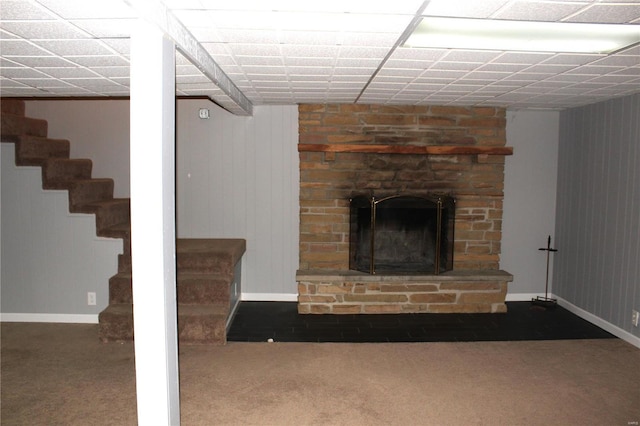 unfurnished living room featuring baseboards, stairway, carpet, a paneled ceiling, and a fireplace