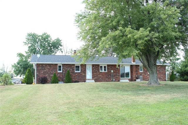 view of front facade with a front yard, brick siding, and central air condition unit