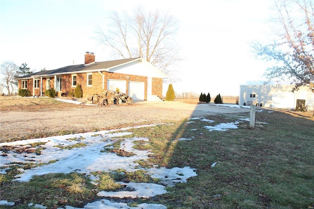 view of side of home with a garage, brick siding, and a chimney