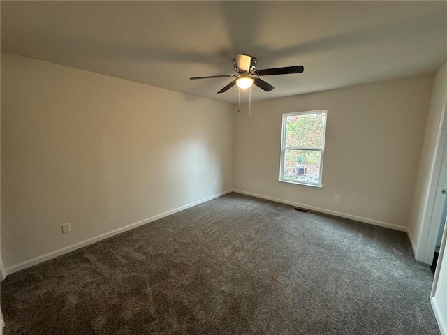 unfurnished room featuring visible vents, baseboards, dark colored carpet, and a ceiling fan