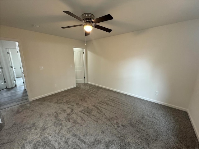 empty room with ceiling fan, dark colored carpet, and baseboards