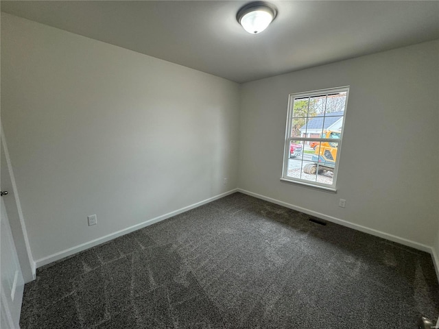 unfurnished room featuring dark colored carpet, visible vents, and baseboards