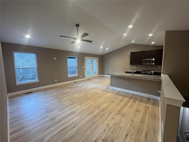 kitchen with lofted ceiling, stainless steel appliances, open floor plan, and light wood-style floors