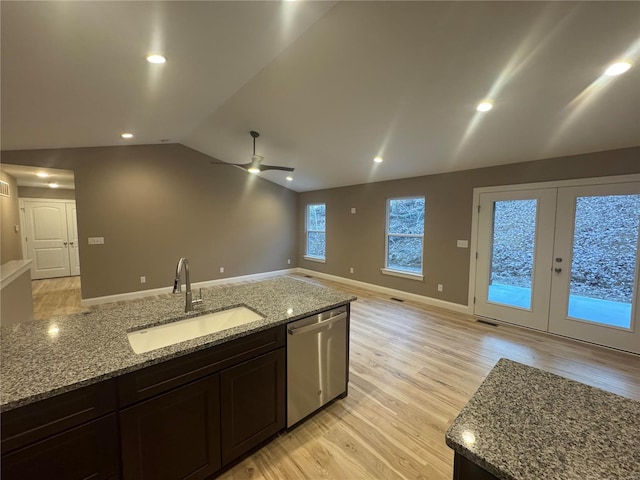 kitchen featuring dishwasher, lofted ceiling, open floor plan, light wood-type flooring, and a sink