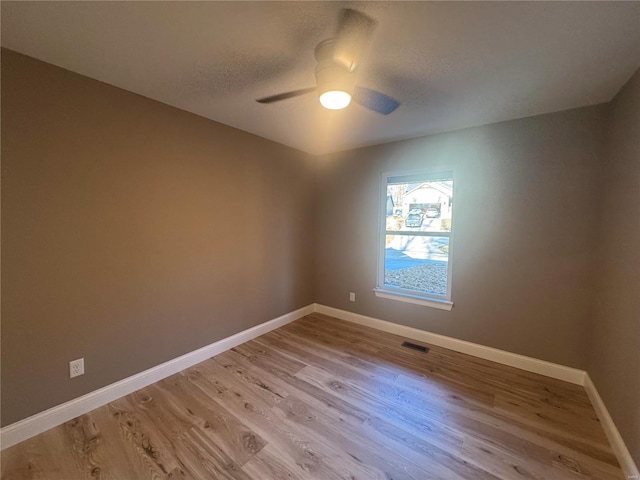 spare room with baseboards, visible vents, ceiling fan, a textured ceiling, and light wood-type flooring