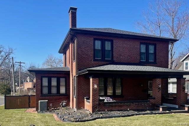 view of front of property with brick siding, central AC unit, a chimney, and a front lawn