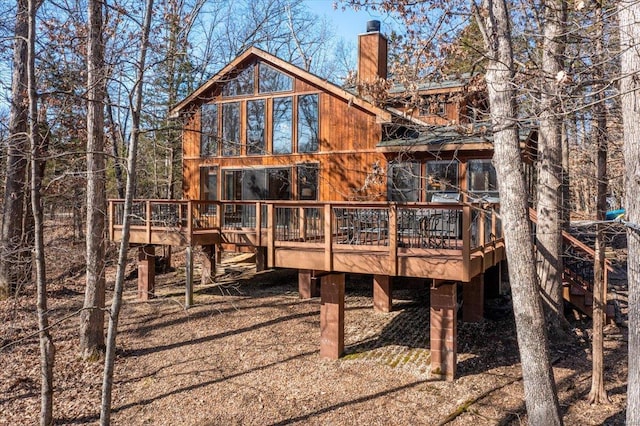 rear view of house featuring a chimney and a wooden deck