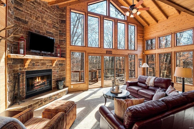 living area with a stone fireplace, wood walls, carpet, and wooden ceiling