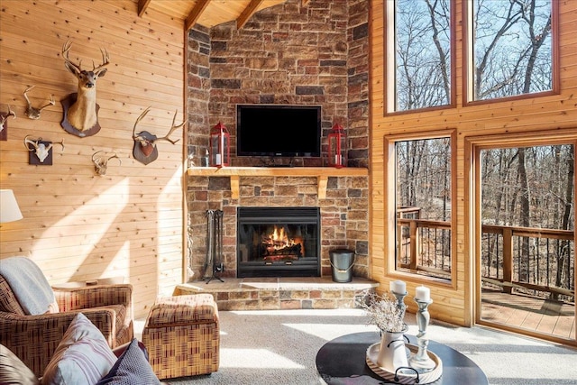 carpeted living room featuring high vaulted ceiling, a large fireplace, wood walls, and beamed ceiling