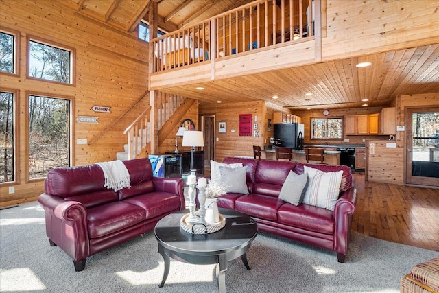 living area with recessed lighting, wooden walls, a high ceiling, wood ceiling, and stairs