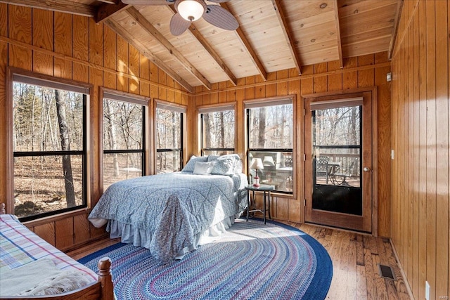 bedroom featuring wood-type flooring, visible vents, lofted ceiling with beams, wood ceiling, and wood walls