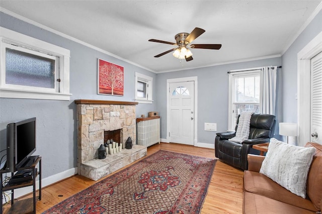 living area with crown molding, wood finished floors, a fireplace, and baseboards