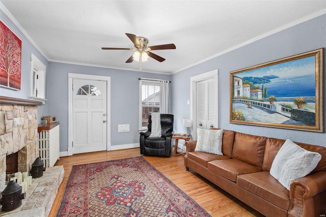 living area with baseboards, a ceiling fan, light wood-style flooring, and crown molding