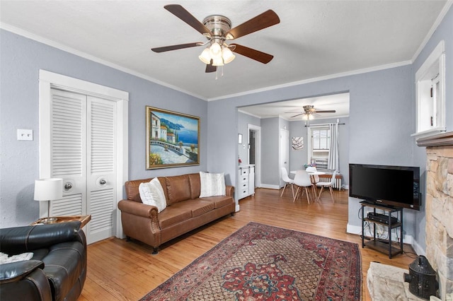 living area with baseboards, wood finished floors, a ceiling fan, and ornamental molding