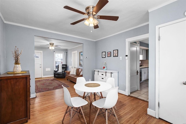 dining room featuring light wood-style flooring, crown molding, baseboards, and ceiling fan