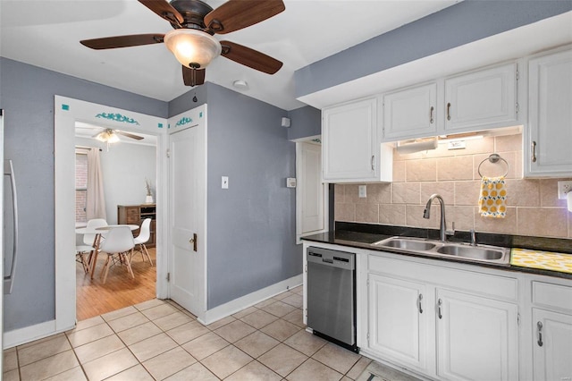 kitchen with dark countertops, a sink, backsplash, light tile patterned floors, and stainless steel dishwasher