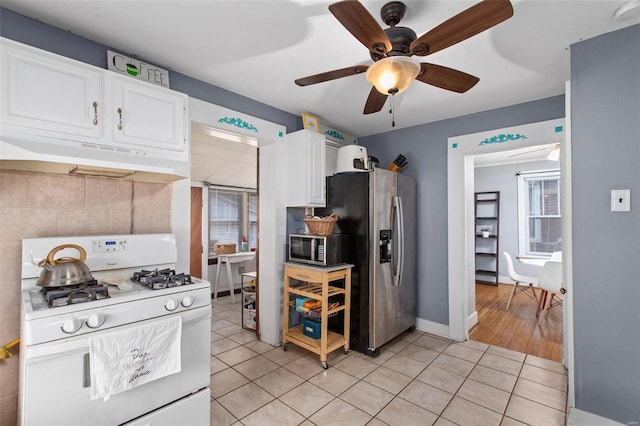 kitchen with light tile patterned floors, ceiling fan, under cabinet range hood, appliances with stainless steel finishes, and white cabinetry