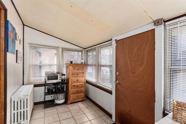 home office with vaulted ceiling, radiator, and light tile patterned floors