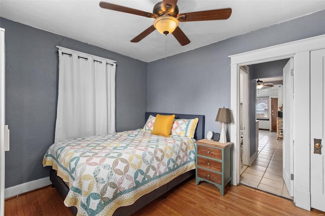 bedroom featuring ceiling fan, baseboards, and wood finished floors