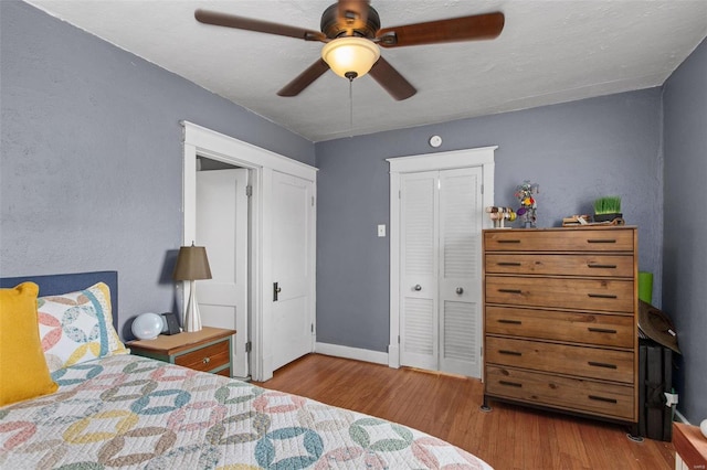 bedroom with a closet, a ceiling fan, baseboards, and wood finished floors